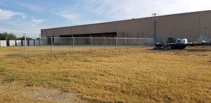 A chain link commercial fence with barbed wire at a commercial building.