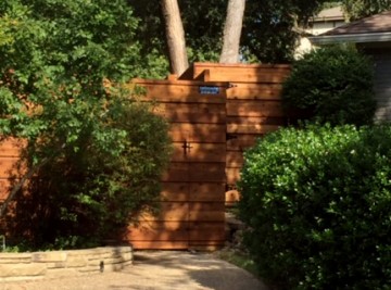 A wood fence surrounded by shrubs.
